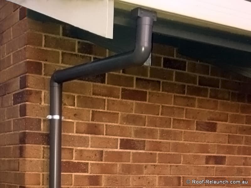 Closeup of newly installed gutter downpipe on brick house