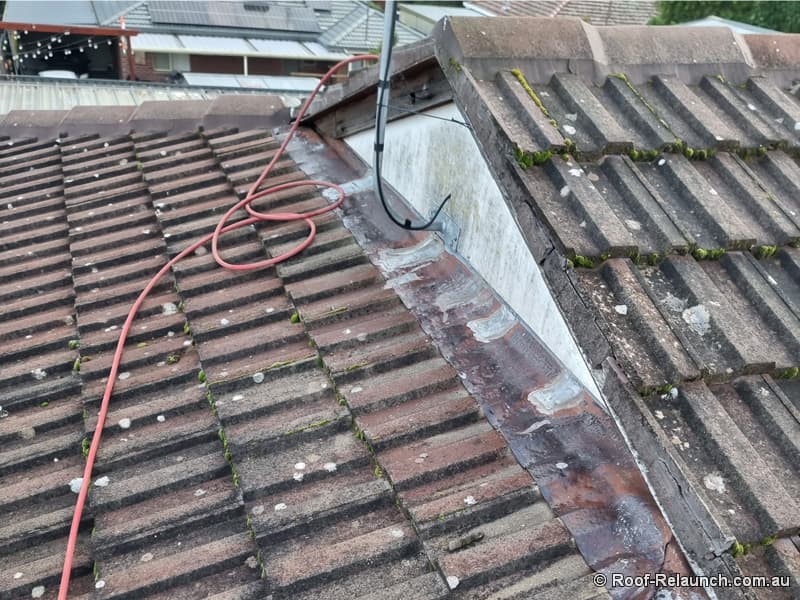 Roof with dirty cement tiles and damaged lead flashing