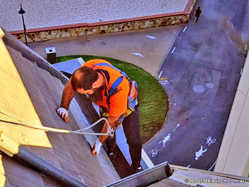 Roofer, replacing tiles on tall building, overlooking a beach